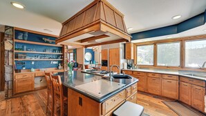 Une cuisine spacieuse avec des meubles en bois, un grand îlot central doté d’un évier et un mur d’accent en pierre.