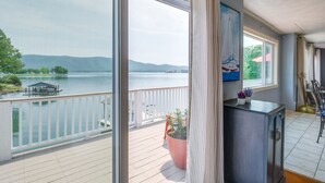 A balcony with a view of a lake and mountains, a dining area with chairs and a table, and a large potted plant. - Waterfront Smith Mountain Lake Home w/ Dock! (Huddleston)
