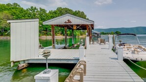A dock with a covered seating area, a boat, and a small building. - Waterfront Smith Mountain Lake Home w/ Dock! (Huddleston)