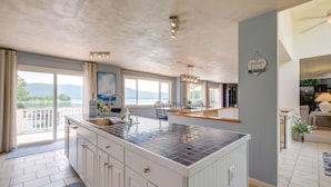 A spacious kitchen with a large island, a dining area with a view, and a living room with a sofa and a lamp. - Waterfront Smith Mountain Lake Home w/ Dock! (Huddleston)