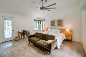 A bedroom with a bed, a sofa, a desk, a chair, a ceiling fan, and a door leading to a balcony. - Bakersfield Oasis: Private Pool, Hot Tub & Patio! (Bakersfield)