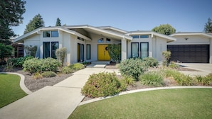 A modern two-story house with a yellow front door, a covered front porch, and a garage. - Bakersfield Oasis: Private Pool, Hot Tub & Patio! (Bakersfield)