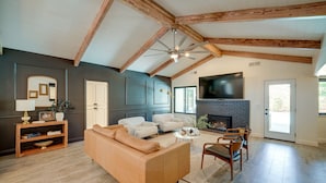 A spacious living room with a large sofa, a fireplace, and a television. - Bakersfield Oasis: Private Pool, Hot Tub & Patio! (Bakersfield)