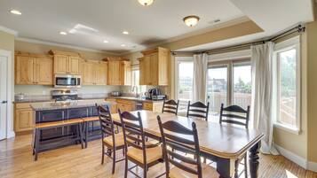 A spacious kitchen with wooden cabinets, a large island, and a dining area with chairs.