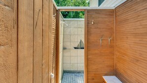 A wooden outdoor shower area with tiled walls and a bench. - Narragansett Vacation Rental Near River & Beach! (Narragansett)