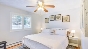 A bedroom with a bed, a ceiling fan, a window with blinds, and framed pictures on the wall. - Narragansett Vacation Rental Near River & Beach! (Narragansett)