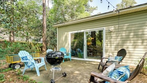 Un patio con mobiliario exterior, una parrilla y un ventanal corredera a un espacio cubierto.