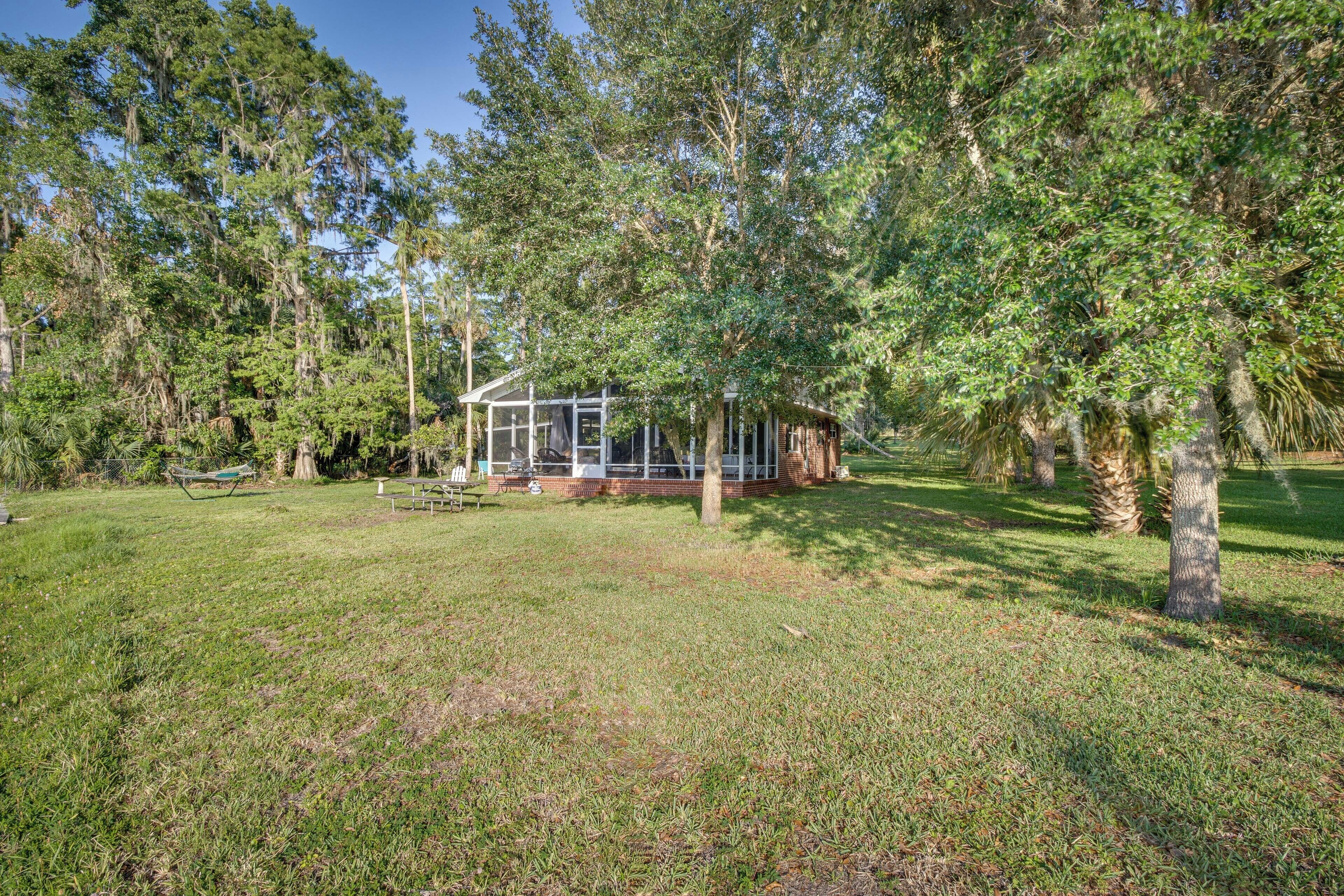 A rustic cabin with a glass enclosure, surrounded by a grassy area and dense trees.