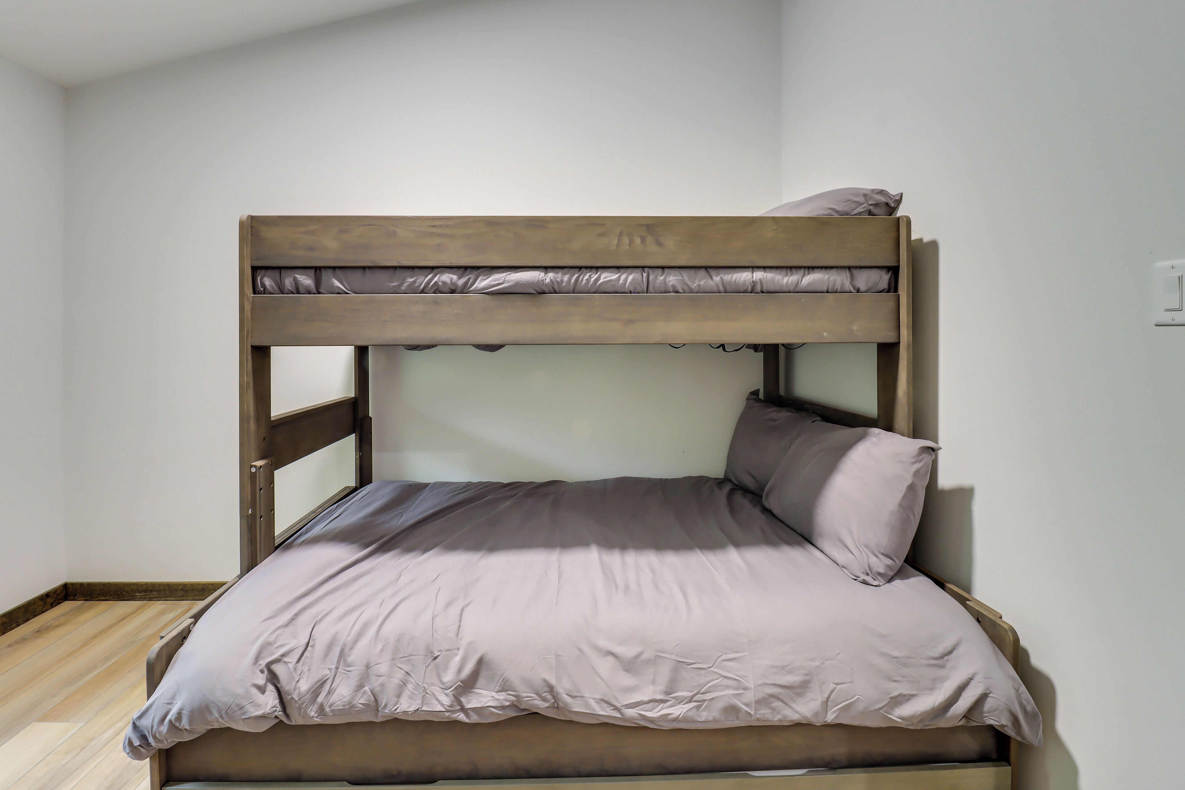 Een stapelbed met houten frame en een matras met een lichtkleurige hoes.
