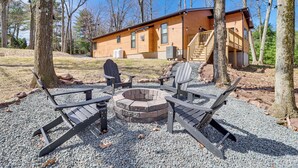 A cabin with a fire pit and Adirondack chairs in a forest setting. - Walk to Water Park: Split-rock Resort Home w/ Deck (Lake Harmony)