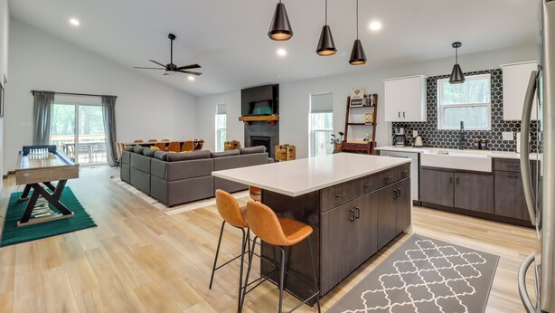 A modern kitchen with a central island, pendant lighting, and a dining area with a table and chairs. - Walk to Water Park: Split-rock Resort Home w/ Deck (Lake Harmony)