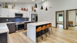 A modern kitchen with a central island, bar stools, and pendant lighting. - Walk to Water Park: Split-rock Resort Home w/ Deck (Lake Harmony)