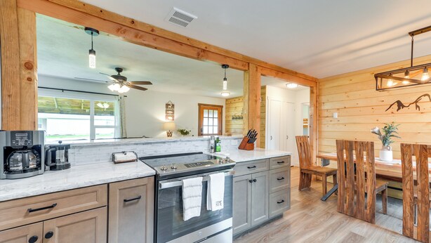 Una cocina moderna con una isla grande, electrodomésticos de acero inoxidable, armarios de madera y un comedor con mesa y sillas de madera.