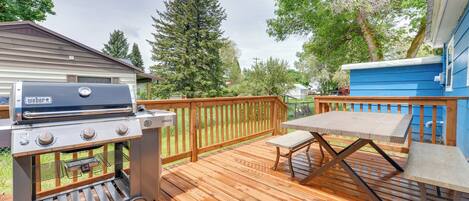Une terrasse en bois avec un barbecue, une table et un banc.