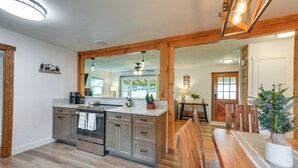Una cocina moderna con vigas de madera, una isla central y un comedor con mesa y sillas de madera.