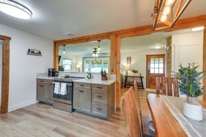 Una cocina moderna con vigas de madera, una isla central y un comedor con mesa y sillas de madera.