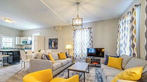 Una sala de estar moderna con un sofá, un sillón amarillo y un televisor.