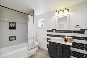 Une salle de bain moderne équipée d’une baignoire, de toilettes et d’un meuble-lavabo.