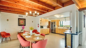 Une cuisine moderne avec des meubles en bois, un réfrigérateur en acier inoxydable et un coin repas comprenant une table en bois et des chaises rouges.