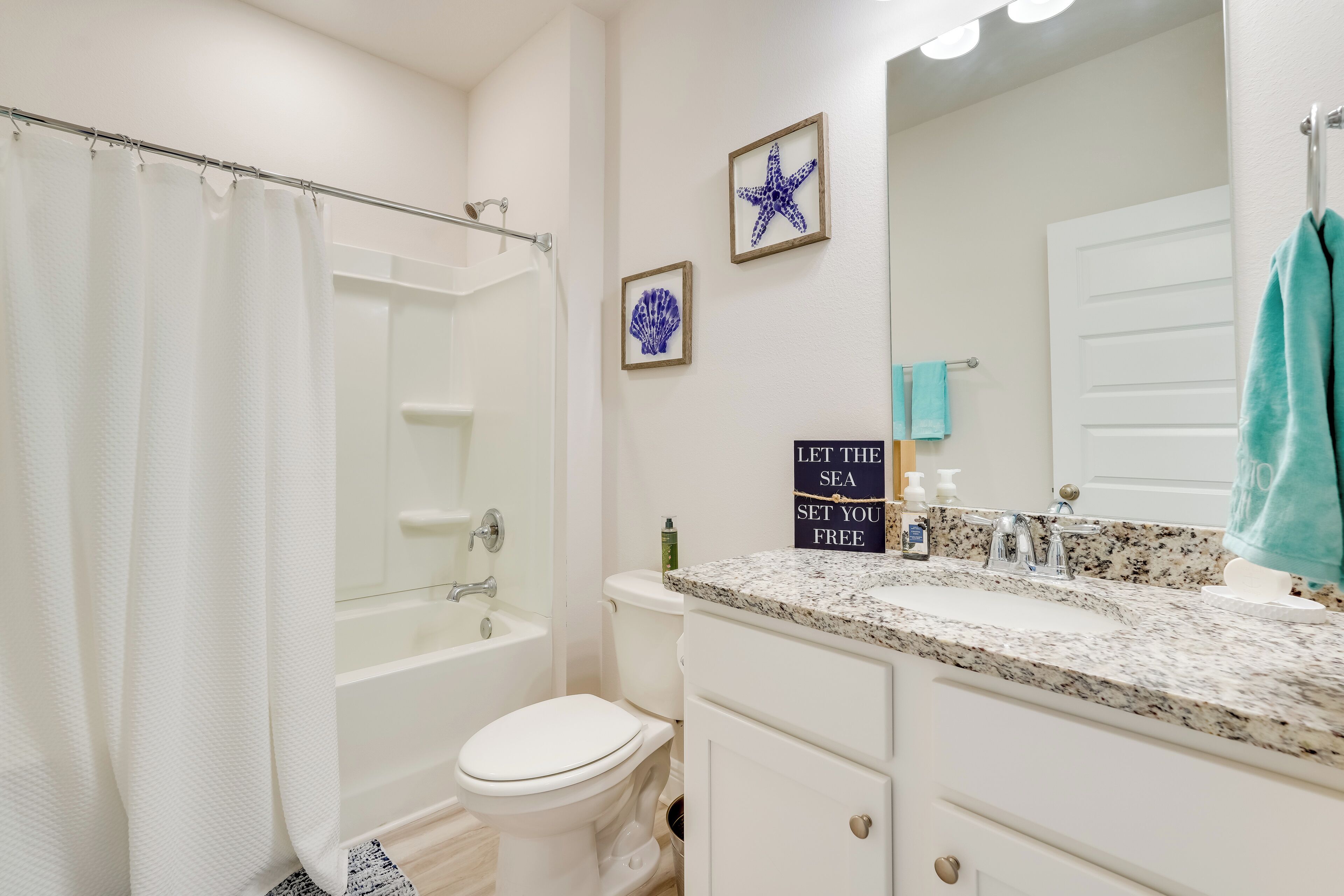 A bathroom with a bathtub, toilet, vanity, and a mirror.