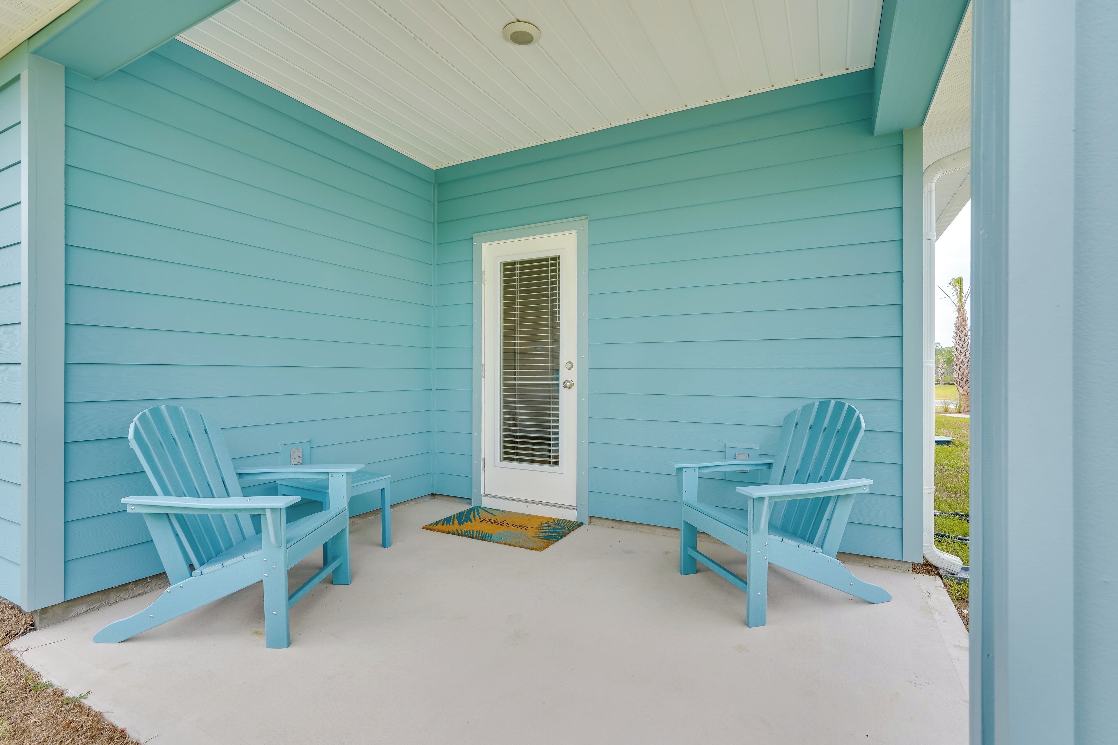 A porch with two Adirondack chairs and a door.