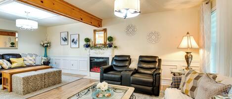 A living room with a fireplace, leather chairs, a sofa, and a coffee table with decorative items.