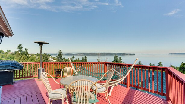 A red deck with outdoor furniture, a hammock, and a view of a lake and mountains. - Federal Way Vacation Rental: Bay & Mountain Views! (Federal Way)