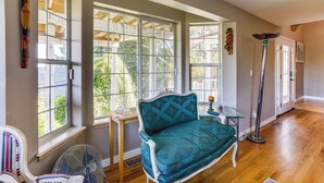 A room with a teal sofa, a standing fan, and large windows with wooden beams. - Federal Way Vacation Rental: Bay & Mountain Views! (Federal Way)