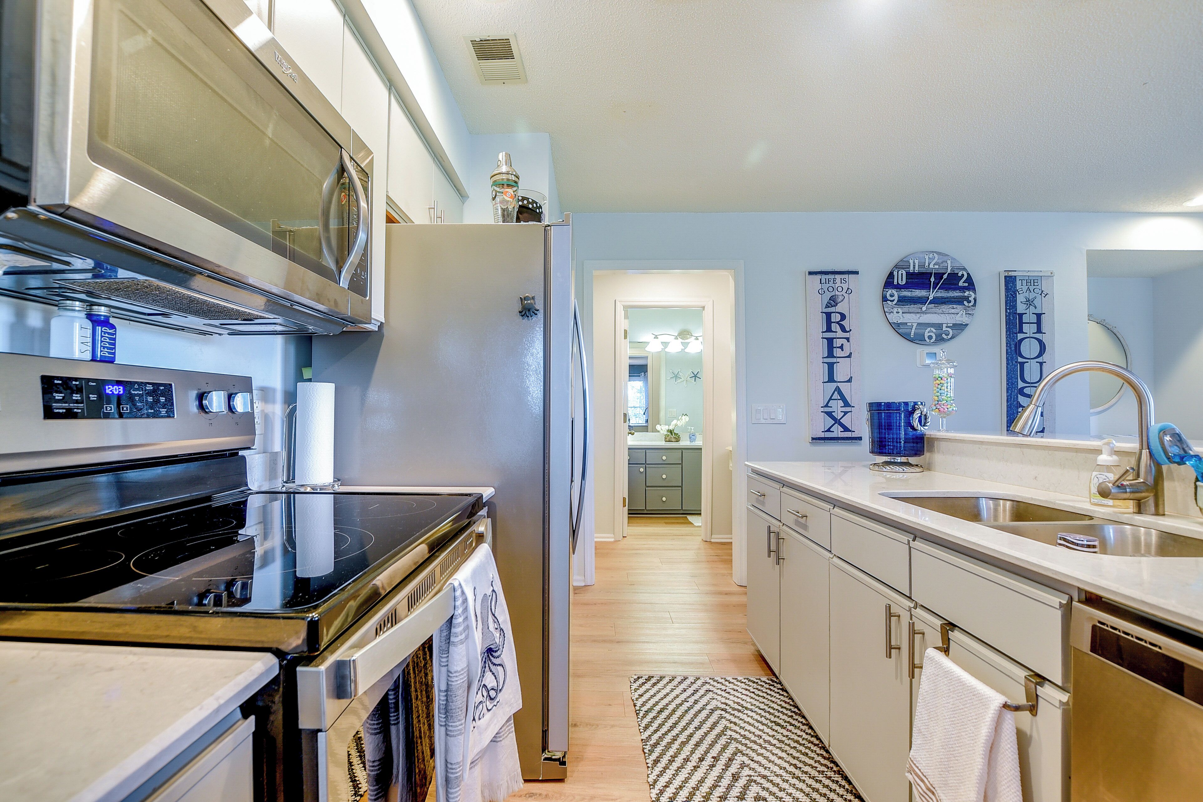 A modern kitchen with stainless steel appliances, a wooden floor, and light blue walls.