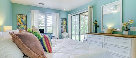 A bedroom with a bed, a dresser, a ceiling fan, and a window with curtains.