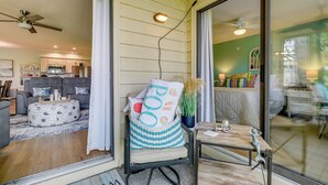 Un salon chaleureux avec un canapé, un pouf rond et un fauteuil agrémenté d’un coussin orné du mot « POO ».