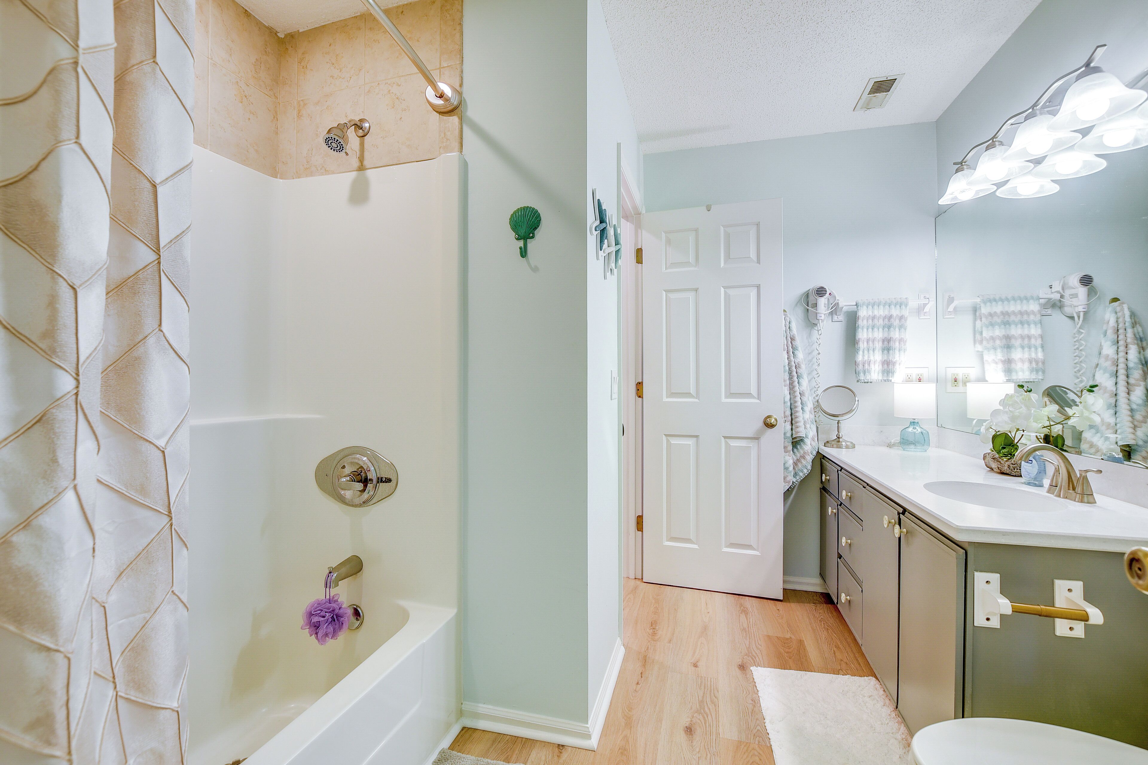 Une salle de bain équipée d’une baignoire, d’une douche, d’un meuble-lavabo avec miroir et de toilettes.