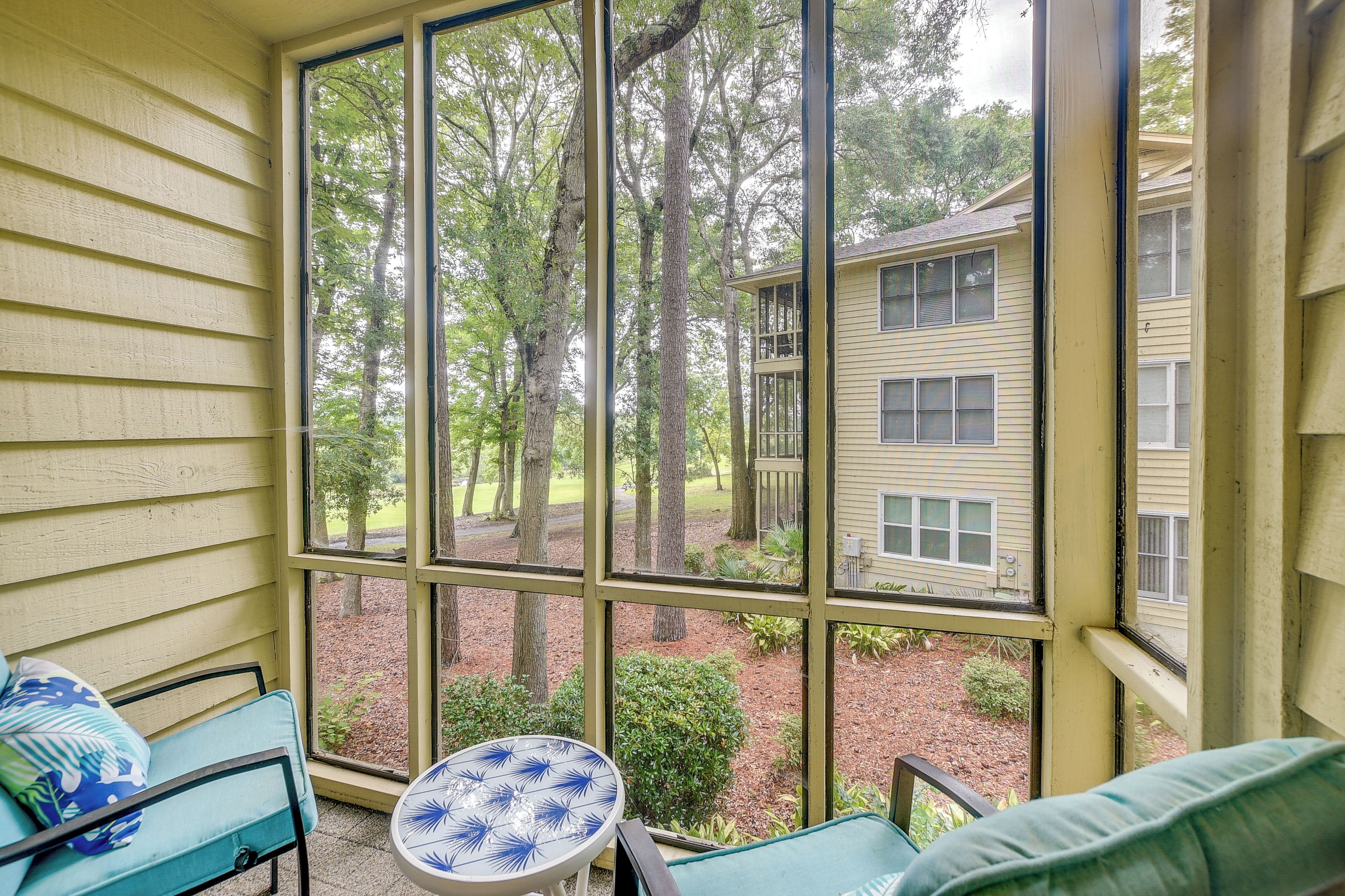 A covered porch with a view of a building and trees.