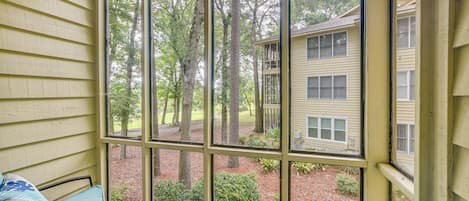 A covered porch with a view of a building and trees.