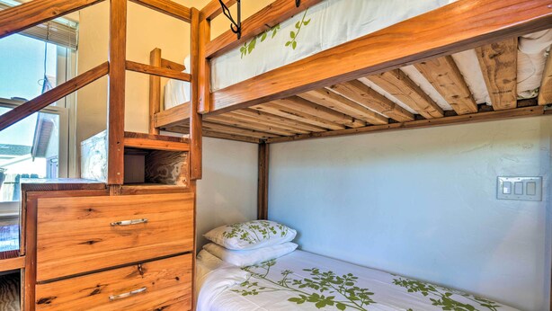 A bunk bed with a wooden ladder, a wooden dresser with drawers, and a white bedspread with green leaf patterns. - San Bruno Vacation Rental - Walk Downtown! (San Bruno)