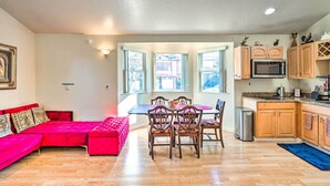 A modern kitchen with wooden cabinets, a microwave, and a dining area with a table and chairs. - San Bruno Vacation Rental - Walk Downtown! (San Bruno)