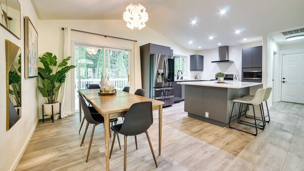 A modern kitchen with a central island, stainless steel appliances, and a dining area with a wooden table and chairs. - Issaquah Retreat Near Lake Sammamish State Park! (Issaquah)