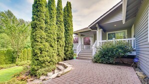 A house with a brick pathway leading to a porch, surrounded by tall evergreen trees and a well-maintained lawn. - Issaquah Retreat Near Lake Sammamish State Park! (Issaquah)