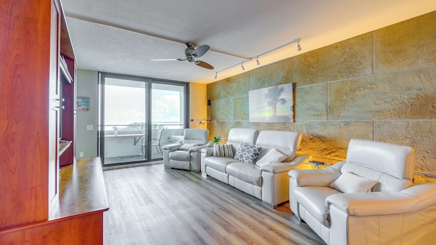 A modern living room with a sofa set, a ceiling fan, and a large window. - Tropical Retreat w/ Pool & Tennis Courts in Hudson (Hudson)
