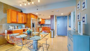 A modern kitchen with wooden cabinets, a stainless steel refrigerator, and a glass dining table with chairs. - Tropical Retreat w/ Pool & Tennis Courts in Hudson (Hudson)