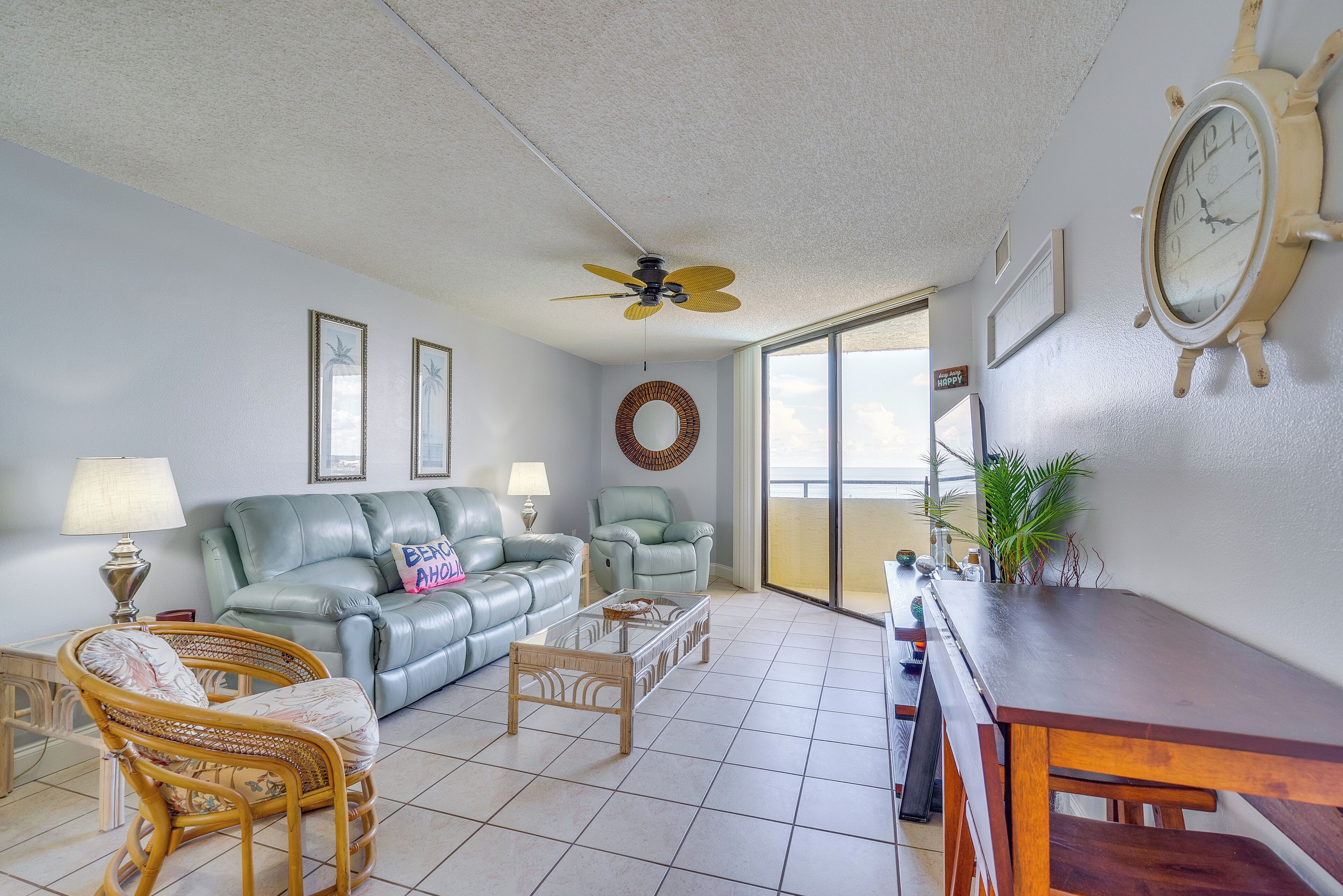 A living room with a sofa, chairs, a coffee table, a ceiling fan, and a dining table.
