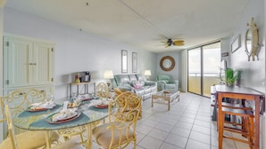 A spacious living area with a dining table set for four, a sofa, and a ceiling fan. - Pool & Beach Access: Waterfront Hudson Condo! (Hudson)