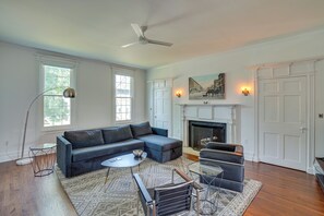 A living room with a sectional sofa, a glass coffee table, a fireplace, and a ceiling fan.