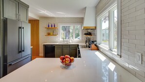 A modern kitchen with a large island, stainless steel appliances, and a bowl of fruit. - Coxsackie Home w/ River Views: Walk to The Wire! (Coxsackie)
