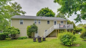 A two-story house with a front porch, a staircase leading to a balcony, and a small patio area with outdoor furniture. - Middletown Vacation Rental: 2 Mi to Beach! (Middletown)