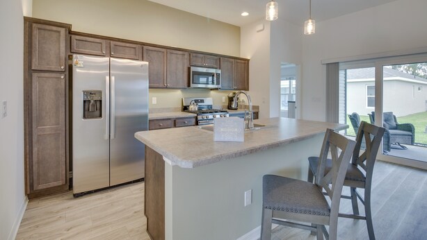 A modern kitchen with a central island, stainless steel appliances, and pendant lighting. - Pool Access: Sleek Home in The Villages w/ Lanai (Wildwood)
