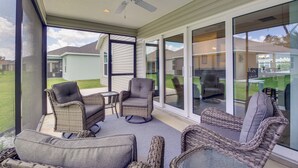 A covered patio with wicker furniture and glass doors leading to a backyard. - Pool Access: Sleek Home in The Villages w/ Lanai (Wildwood)