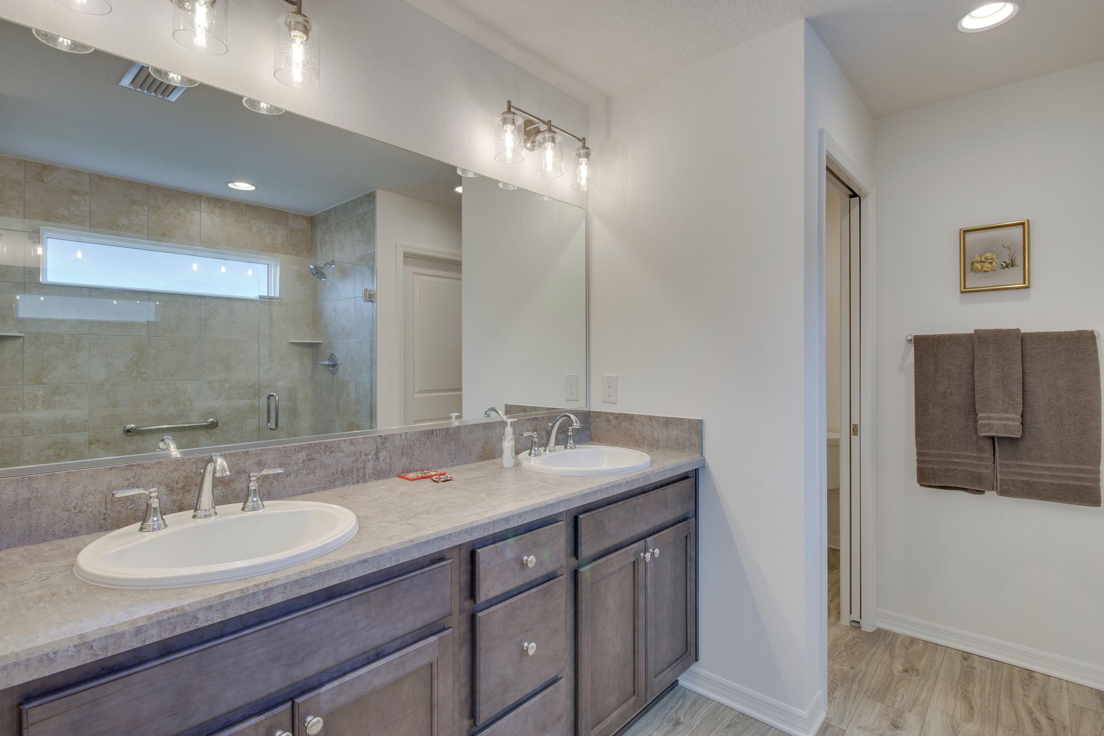 A bathroom with two sinks, a large mirror, and a towel rack.