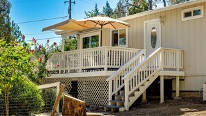 A two-story building with a balcony, a staircase, and a covered outdoor area with an umbrella. - Groveland Vacation Rental w/ Private Deck & Grill! (Groveland)
