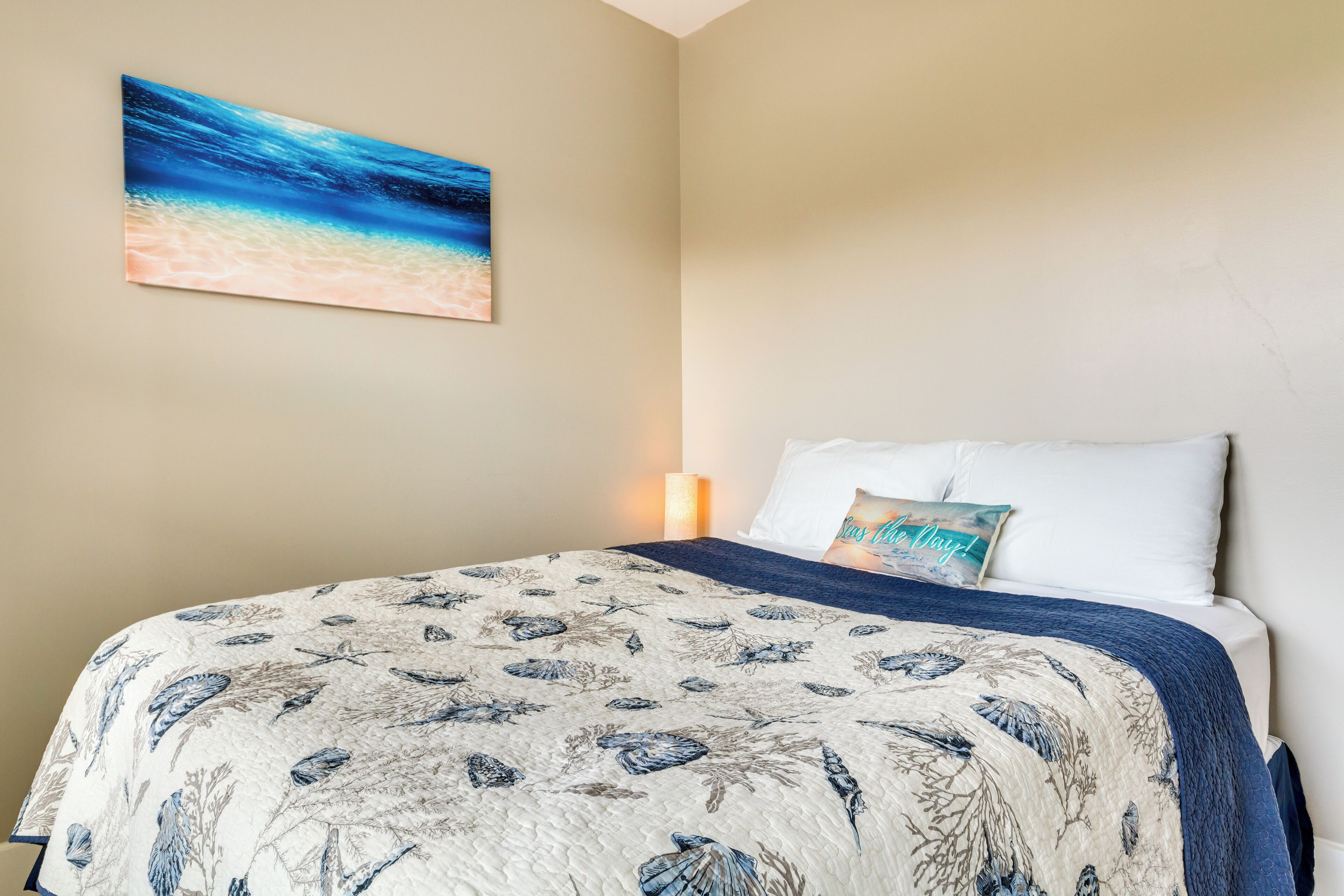 Une chambre à coucher avec un lit, un tableau accroché au mur et une lampe de chevet.